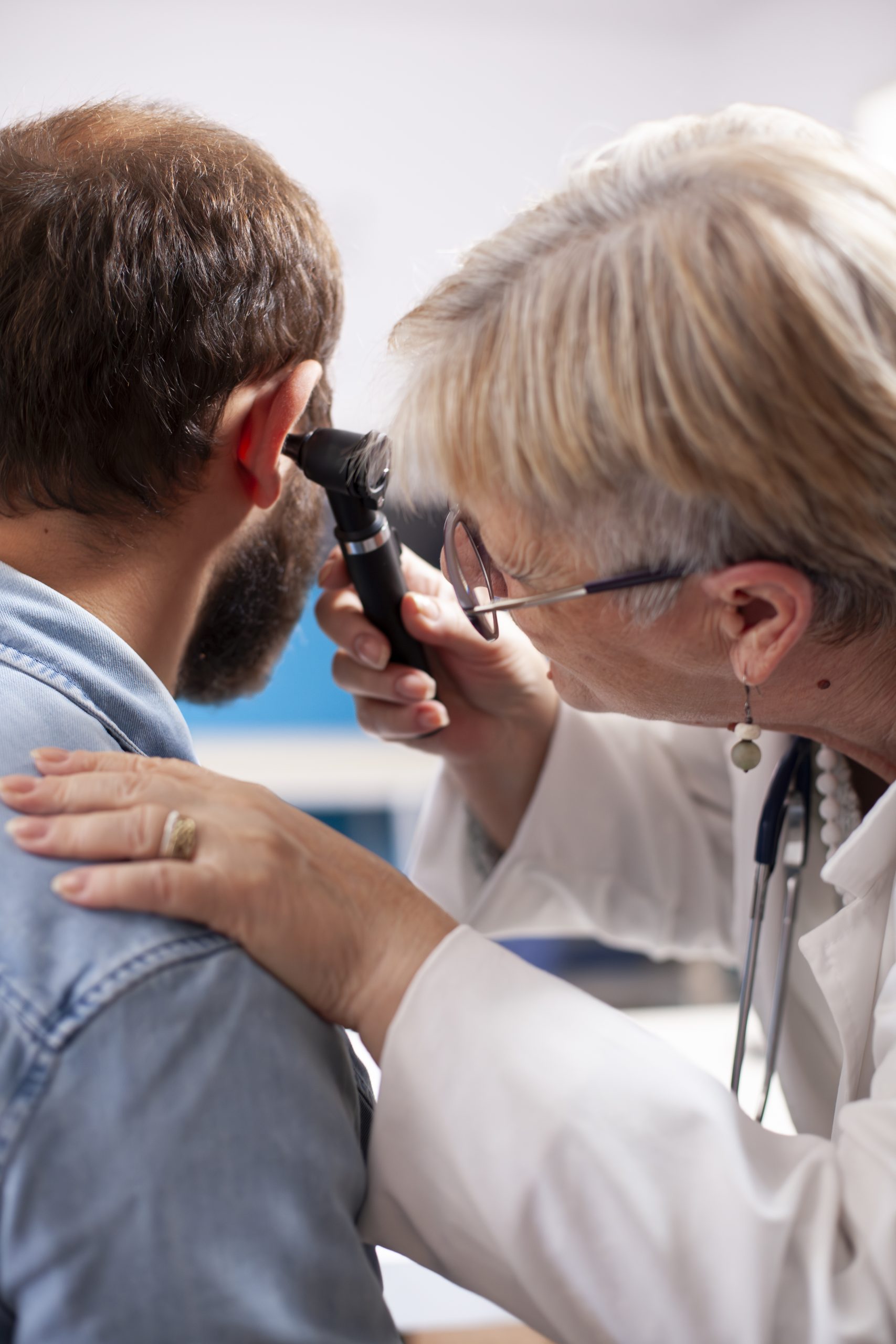 physician uses otoscope on young man